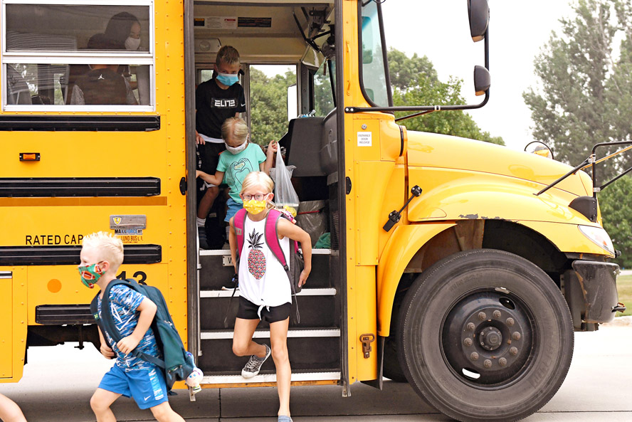 Kids getting off school bus with masks in pandemic