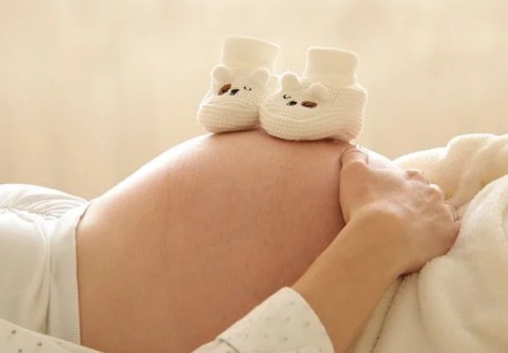 pregnant woman laying down with booties on belly